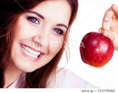 Woman holds apple fruit close to face, isolated 135276066