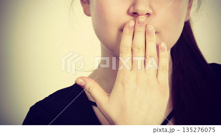 Woman covering her mouth with hand 135276075