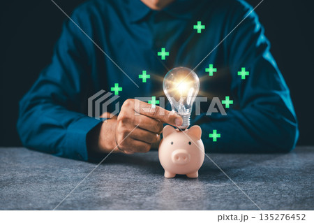 Financial innovation concept shows hand putting glowing lightbulb into piggy bank for wealth growth, representing creative business ideas and smart financial investment strategies Financial innovation concept shows hand putting glowing lightbulb into piggy bank for wealth growth, representing creative business ideas and smart financial investment strategies 135276452