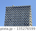 Modern Skyscraper Facade with Checkerboard Pattern Against Blue Sky 135276599