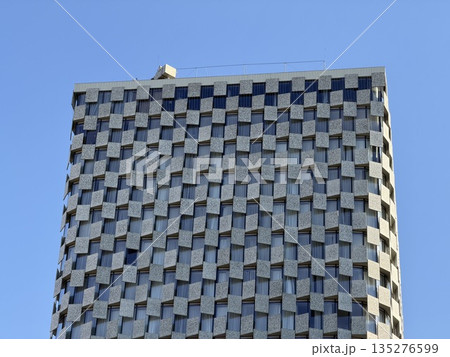 Modern Skyscraper Facade with Checkerboard Pattern Against Blue Sky 135276599