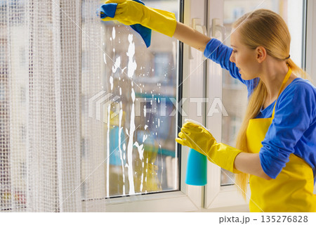 Woman cleaning window at home Woman cleaning window at home 135276828