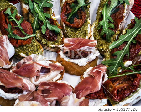 Bruschetta with sun-dried tomatoes, pesto greens and lettuce leaves on toasted slices of bread 135277528
