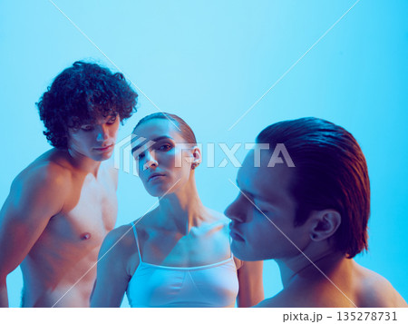 Two men and woman with soft gaze and sculpted skin in blue light. 135278731
