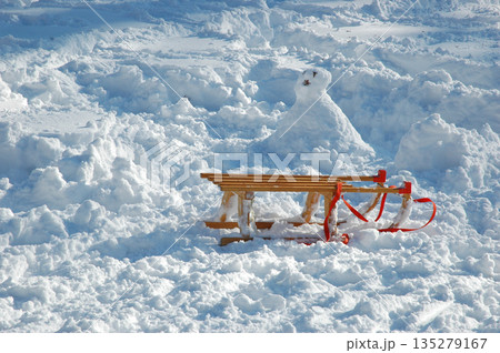 Traditional wooden sled and snowman in deep white snow Traditional wooden sled and snowman in deep white snow 135279167