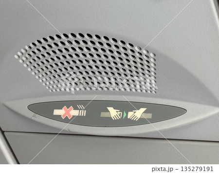 Airplane overhead seat belt sign panel. Inflight instruction, passenger safety, and aircraft regulation through illuminated aviation symbols 135279191
