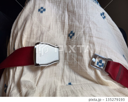 Aircraft seat belt opened on passenger seat. Inflight readiness, movement freedom, and cabin transition through aviation safety equipment 135279193