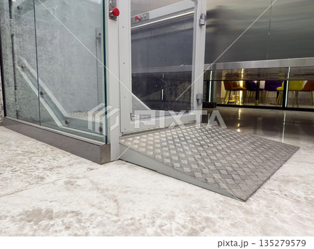 Wheelchair ramp at entrance to accessible elevator. Fully equipped office with ramp and elevator for employees with disabilities. Accessible office space for people with mobility issues Wheelchair ramp at entrance to accessible elevator. Fully equipped office with ramp and elevator for employees with disabilities. Accessible office space for people with mobility issues 135279579