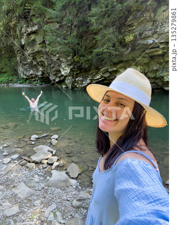 Woman Taking Selfie by River with Swimmer 135279861