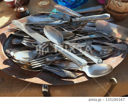 Antique flea market in Europe, Italy. Vintage items. Set of old tableware. Retro knives and spoons, background for design. 135280167