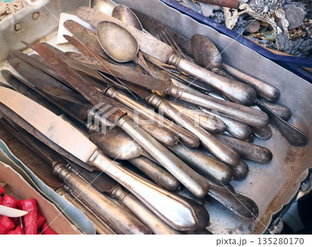 Antique flea market in Europe, Italy. Vintage items. Set of old tableware. Retro knives and spoons, background for design. Antique flea market in Europe, Italy. Vintage items. Set of old tableware. Retro knives and spoons, background for design. 135280170