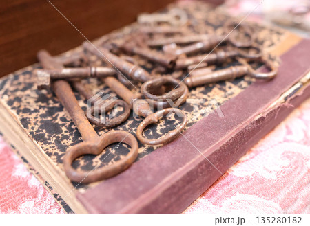 Antique flea market in Europe, Italy. Vintage items. Set of rusty iron keys on book in town. Retro items for background decoration. 135280182