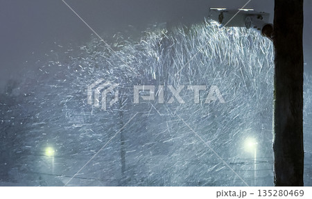 A dramatic night scene of a heavy blizzard, with a street light illuminating swirling, wind-blown snow against a dark, cold sky, capturing the raw intensity of a winter storm. A dramatic night scene of a heavy blizzard, with a street light illuminating swirling, wind-blown snow against a dark, cold sky, capturing the raw intensity of a winter storm. 135280469