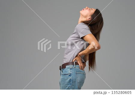Woman arching back with hands on waist in discomfort, looking upward, Woman arching back with hands on waist in discomfort, looking upward, 135280605