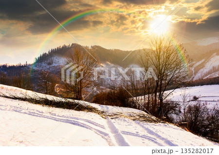 winter landscape with snow covered forested hills at sunset. mountains in cold weather in evening light. rural scene. christmas holiday in alpine region. storytelling cinematic image under the rainbow winter landscape with snow covered forested hills at sunset. mountains in cold weather in evening light. rural scene. christmas holiday in alpine region. storytelling cinematic image under the rainbow 135282017