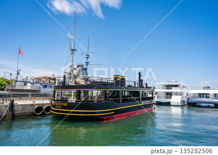 横須賀・三笠桟橋に停泊する猿島航路の遊覧船と記念艦三笠 135282506