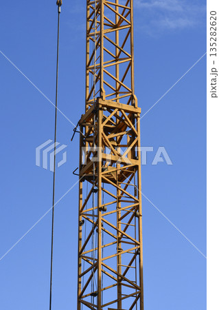 Yellow Tower Crane Mast Against Blue Sky Yellow Tower Crane Mast Against Blue Sky 135282620