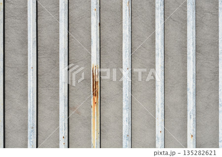 Weathered White Metal Bars on Grey Stone Wall 135282621