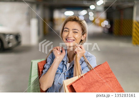 A smiling woman with shopping bags is happy after a successful shopping trip A smiling woman with shopping bags is happy after a successful shopping trip 135283161