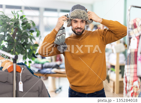 Young man choosing hat in clothing store Young man choosing hat in clothing store 135284018