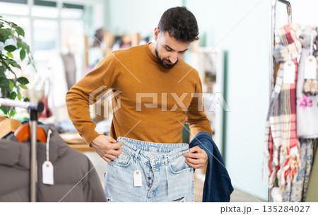 Young man choosing jeans in clothing store Young man choosing jeans in clothing store 135284027