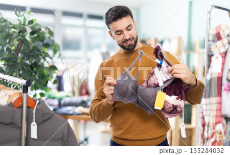 Man choosing a set of underwear for his wife Man choosing a set of underwear for his wife 135284032