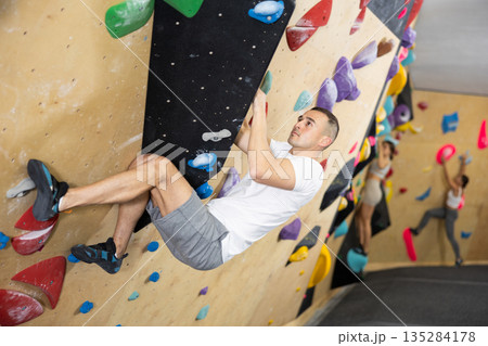 Young man practicing rock climbing on climbing wall Young man practicing rock climbing on climbing wall 135284178