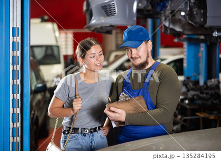 Mechanic guy signs agreement with young woman client Mechanic guy signs agreement with young woman client 135284195