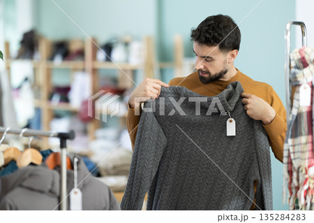 Young man choosing sweater in clothing store 135284283