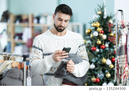 Young man scanning qr code of sweater in store Young man scanning qr code of sweater in store 135284300