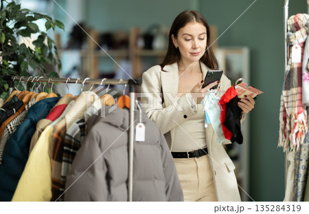 Young woman scanning QR-code on panties in clothing store Young woman scanning QR-code on panties in clothing store 135284319