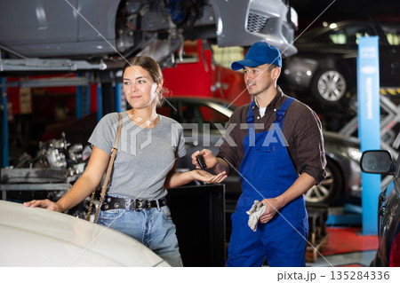 Young male mechanic giving car keys to woman client 135284336