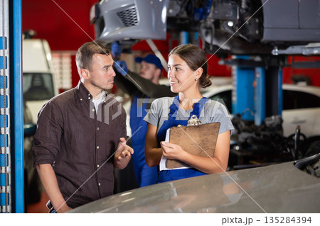 Mechanic woman signs agreement with young man client 135284394