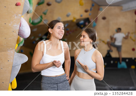 Two young women talking near climbing wall Two young women talking near climbing wall 135284428