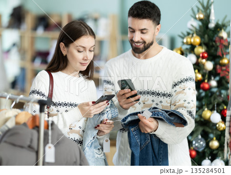 Couple scanning barcode on jeans with Christmas tree background Couple scanning barcode on jeans with Christmas tree background 135284501