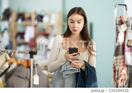Young woman scans qr code of jeans in store Young woman scans qr code of jeans in store 135284528