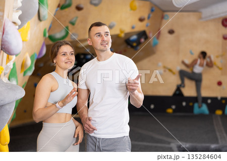 Girl gym coach and teen client standing in fitness room discussing possible options climbing Girl gym coach and teen client standing in fitness room discussing possible options climbing 135284604