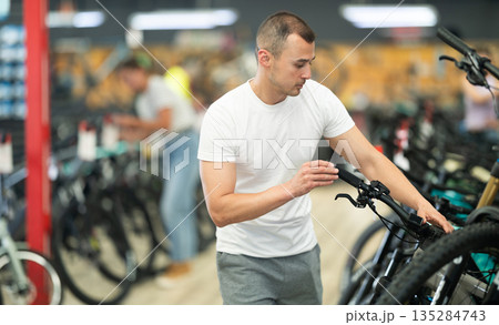Young man choosing bike in store Young man choosing bike in store 135284743
