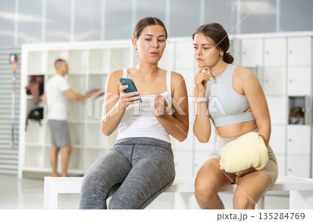Girls sitting with smartphone in climbing gym locker area Girls sitting with smartphone in climbing gym locker area 135284769