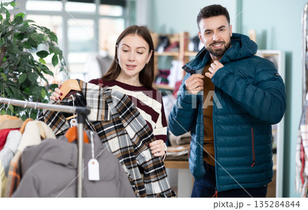 Woman looking at coat next to man trying on jacket 135284844