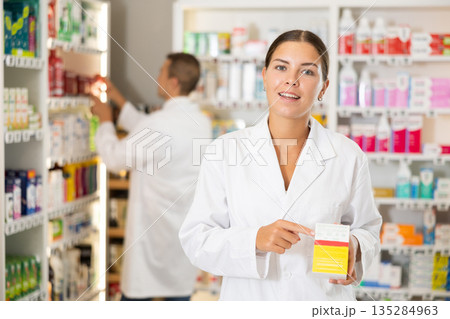 Young female pharmacist offering preparation in box Young female pharmacist offering preparation in box 135284963