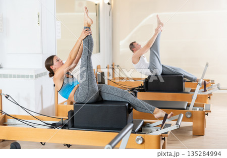 Female athletic girl doing stretching on pilates machine in pilates studio 135284994