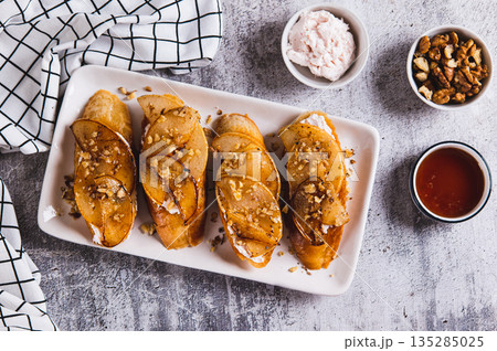 Sweet sandwiches with ricotta, baked pear, honey and nuts on a plate on the table top view 135285025