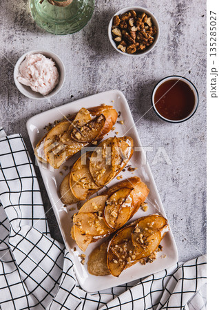 Delicious toasts with cream cheese, fried pear and honey on a plate top and vertical view Delicious toasts with cream cheese, fried pear and honey on a plate top and vertical view 135285027