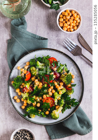 Mix of chickpeas, tomatoes, broccoli and parsley on a plate on the table top and vertical view Mix of chickpeas, tomatoes, broccoli and parsley on a plate on the table top and vertical view 135285056