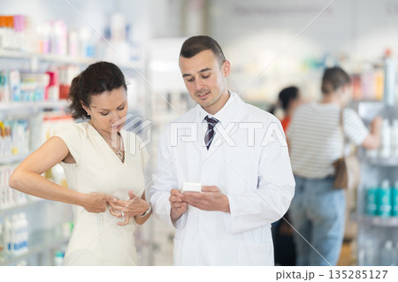Male pharmacist advises medicine for heart pain to woman 135285127