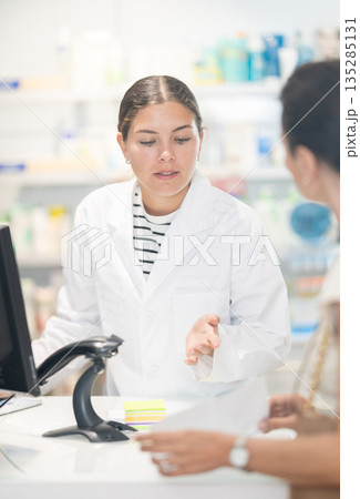 Female pharmacist at the cash register selling medicine to pharmacy visitor 135285131