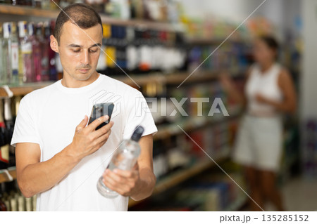 Young man scanning qr code for vodka 135285152