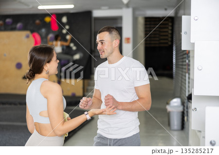 Climbing coach instructing female student by gym lockers before training 135285217