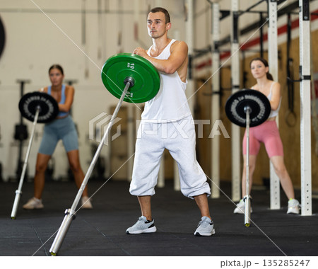 Young man training with barbell in gym 135285247